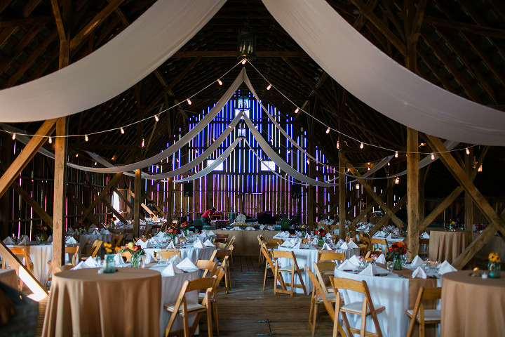 wedding reception adorned with silks, string lights, white cloth tables, and rustic chairs